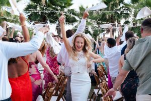 Novia celebrando su boda en Hacienda Las Mesas, Jerez de la Frontera, rodeada de invitados felices ondeando servilletas al aire. Fotografía natural de EsebeWedding.